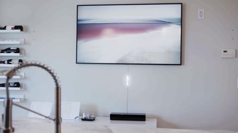 A framed landscape artwork displayed on a white wall above a minimalist desk with a faucet and decorative items