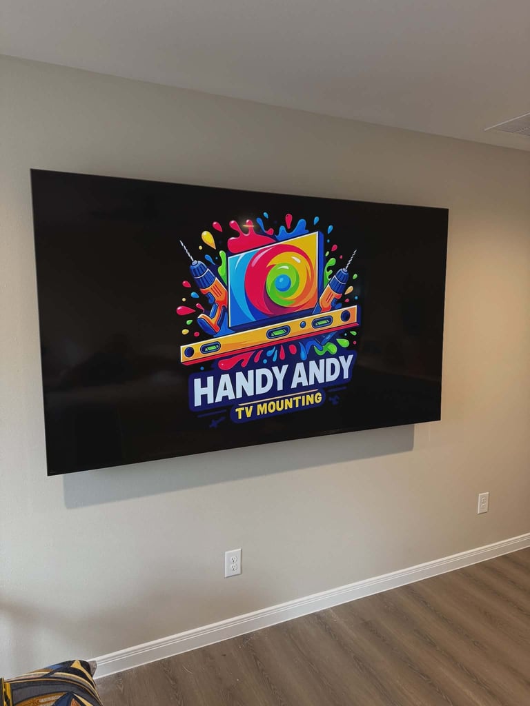 Wall-mounted flat screen TV displaying colorful Handy Andy TV Mounting logo with level tool design on cream-colored wall