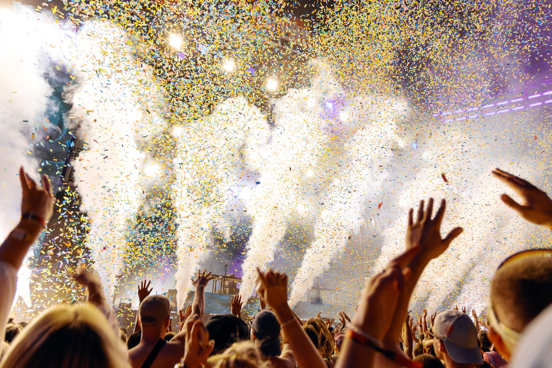 People Cheering and Dancing under Confetti at Austin Music Festival with intense light show