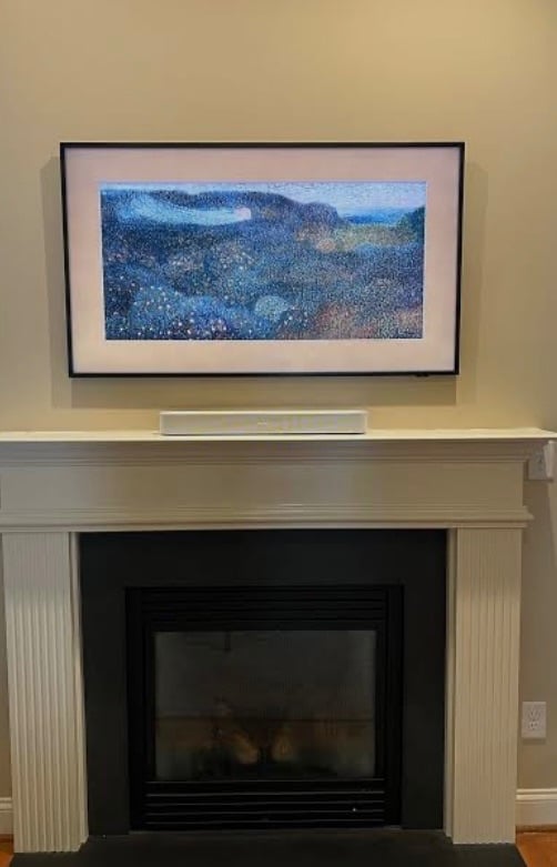Samsung Frame TV mounted above a fireplace blending as artwork in a bright, modern Dallas living room