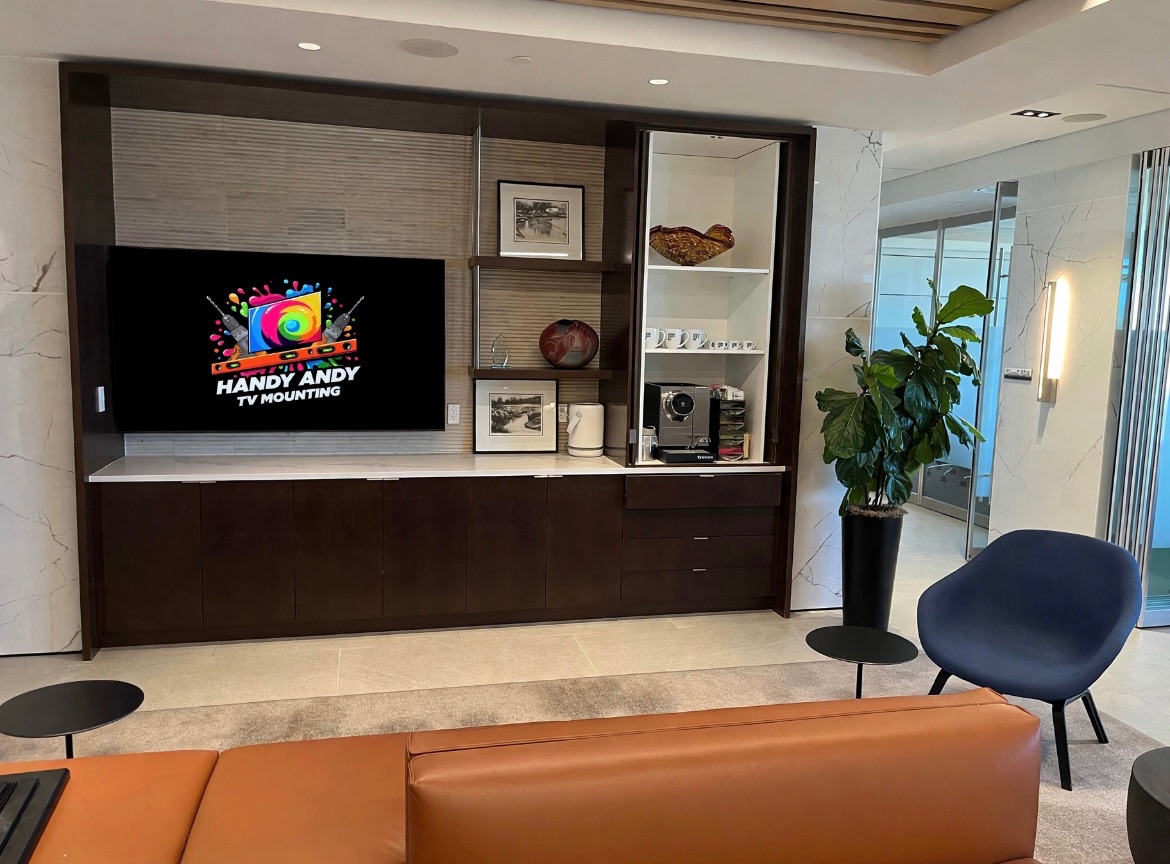 TV mounted above a marble-tiled media wall with dark wood built-in cabinetry in a client's living room