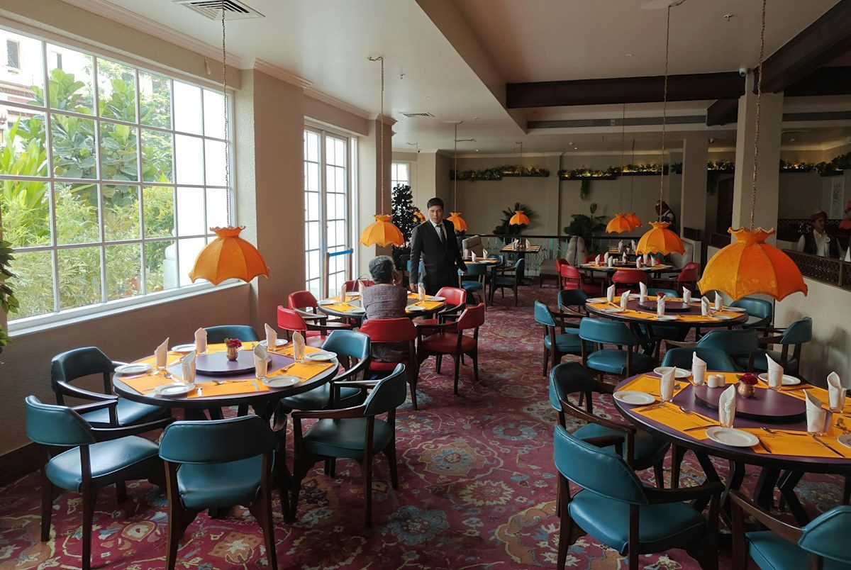 Restaurant dining room with round tables and orange pendant lights
