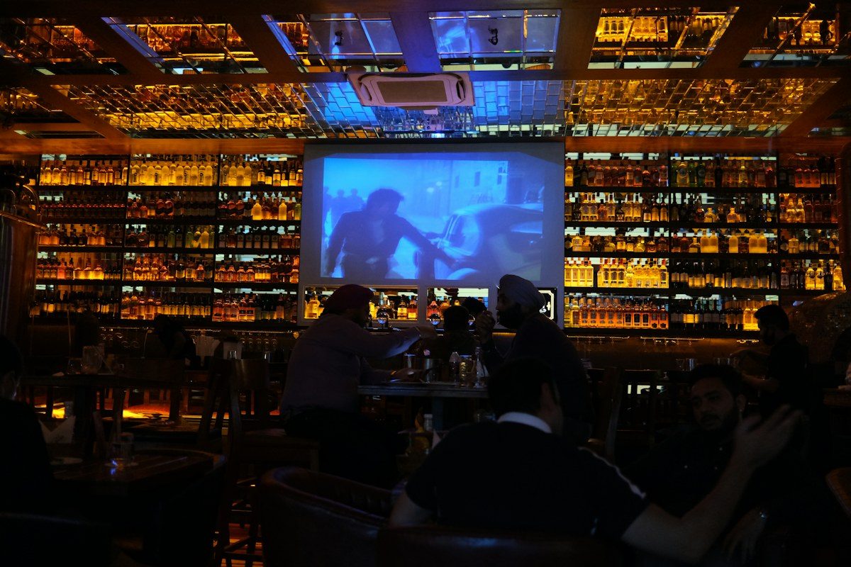 Dim bar with a large screen above the liquor shelves