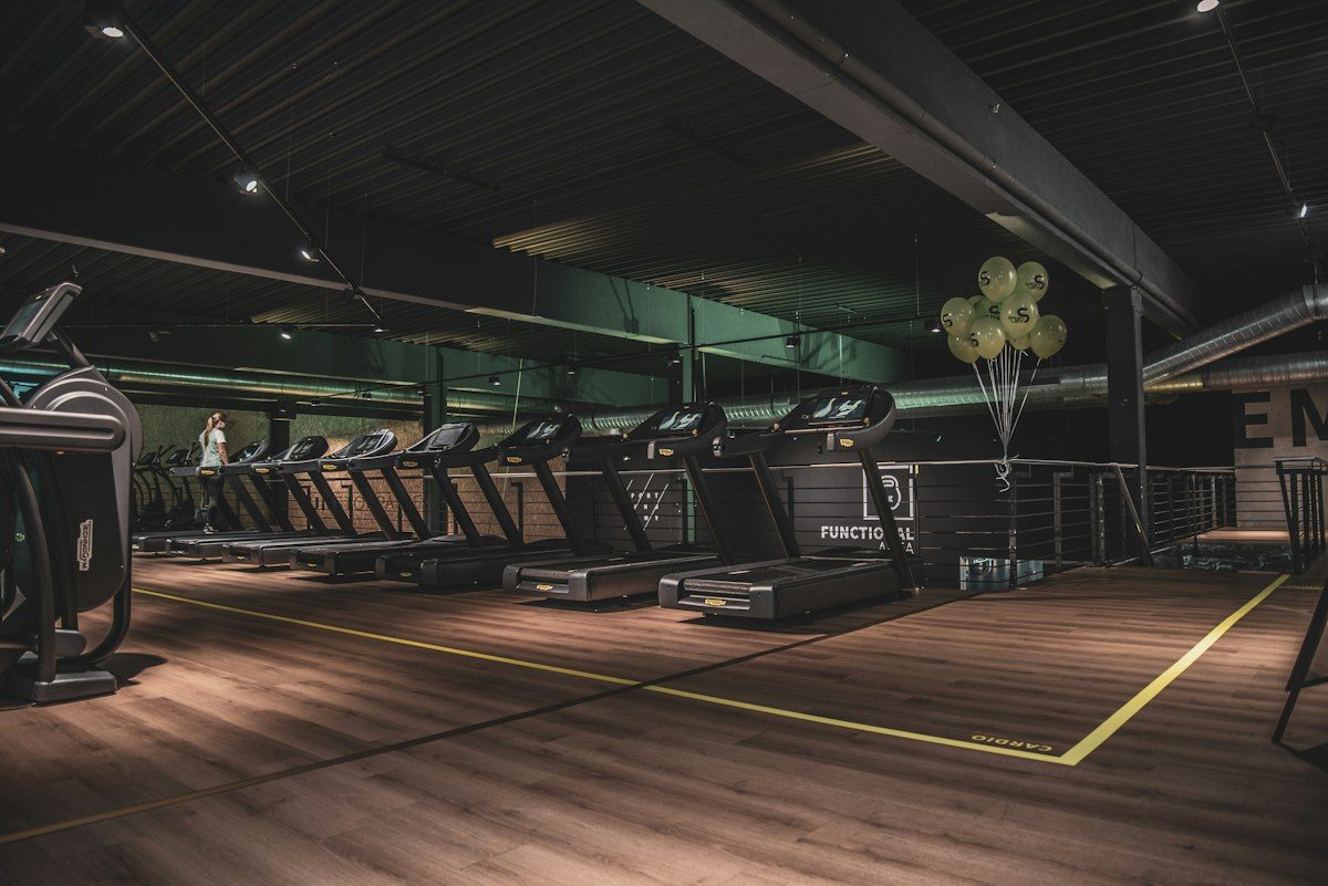 Gym with rows of treadmills on a wood floor