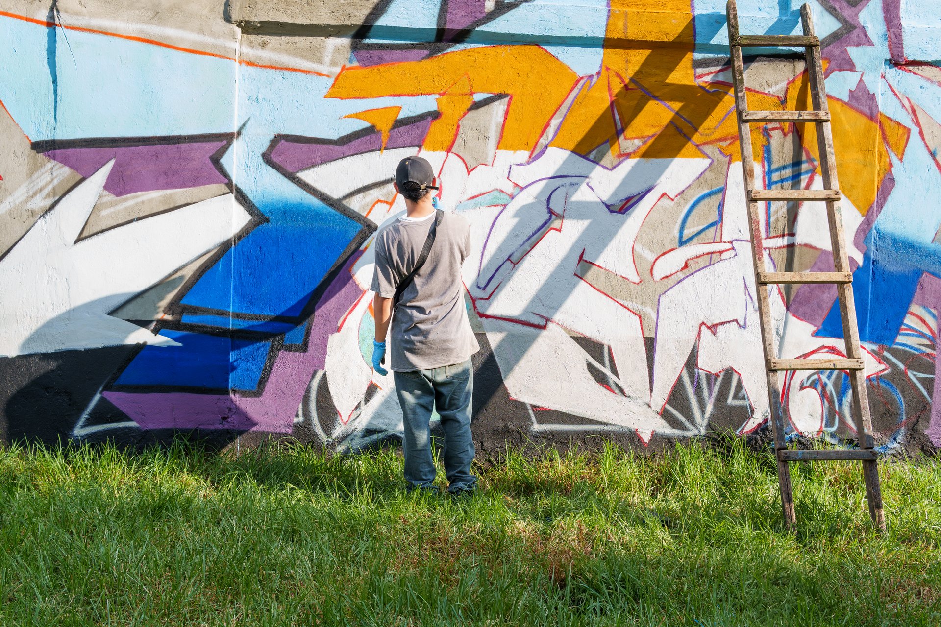 Graffiti artist painting colorful street art on a concrete wall in Houston using spray paint, showcasing urban creativity and self-expression