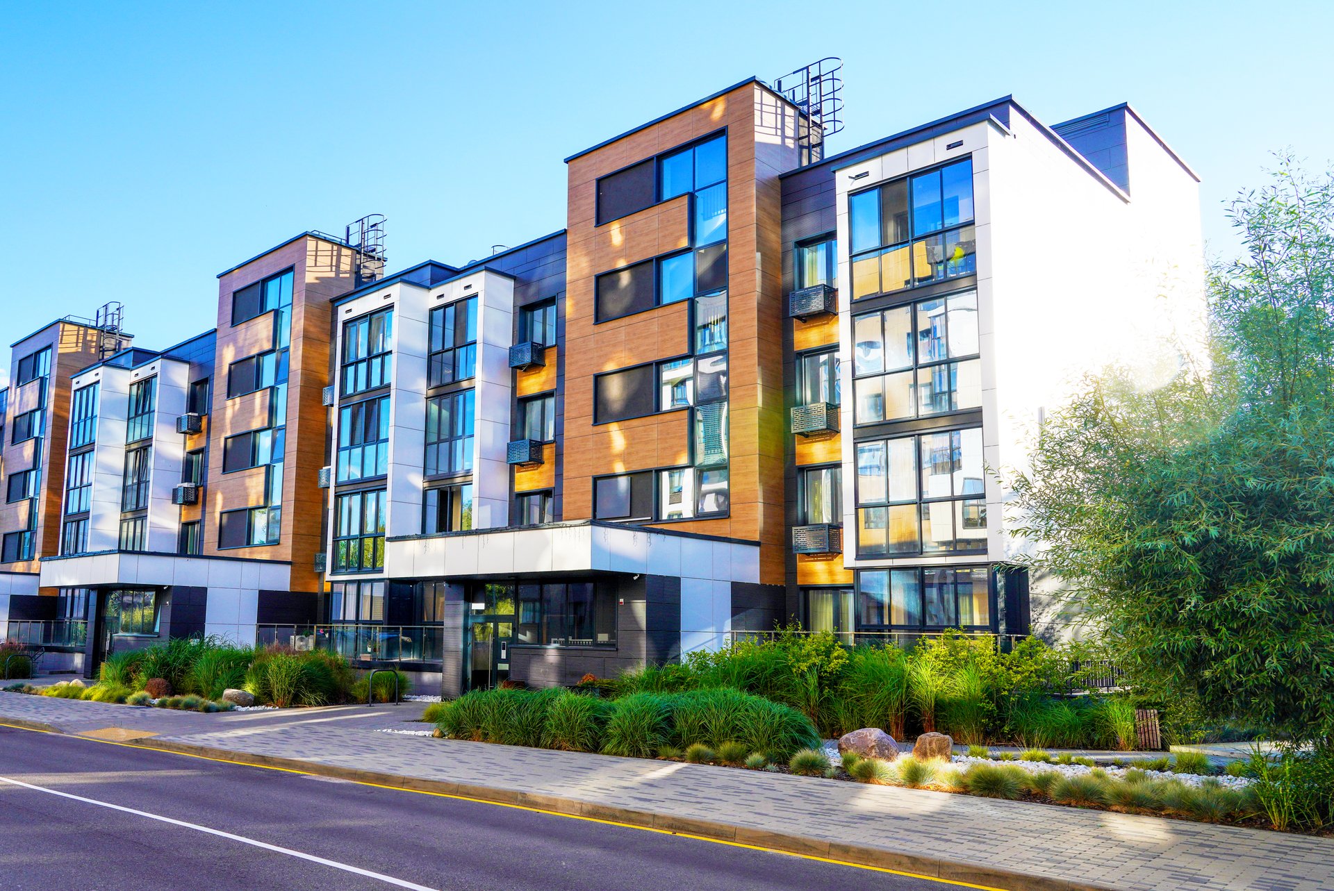 Modern residential building in contemporary architecture. Landscaping for urban spaces. Modern apartment Facade in green environment. Landscape design in Condominium. Entrance to residential building.
