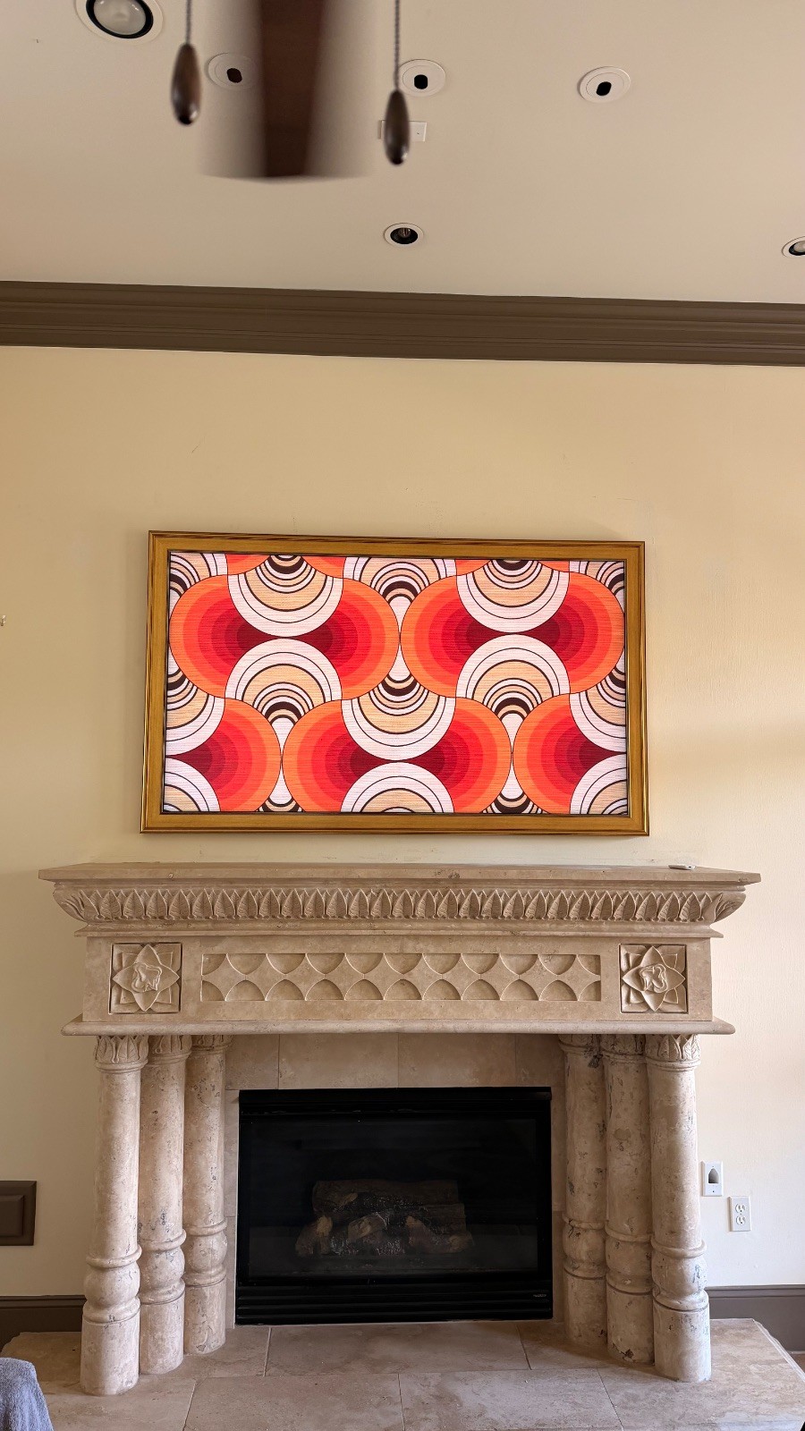 Finished Samsung Frame TV with a custom gold bezel in art mode above a carved stone fireplace, installed by Juan in Houston