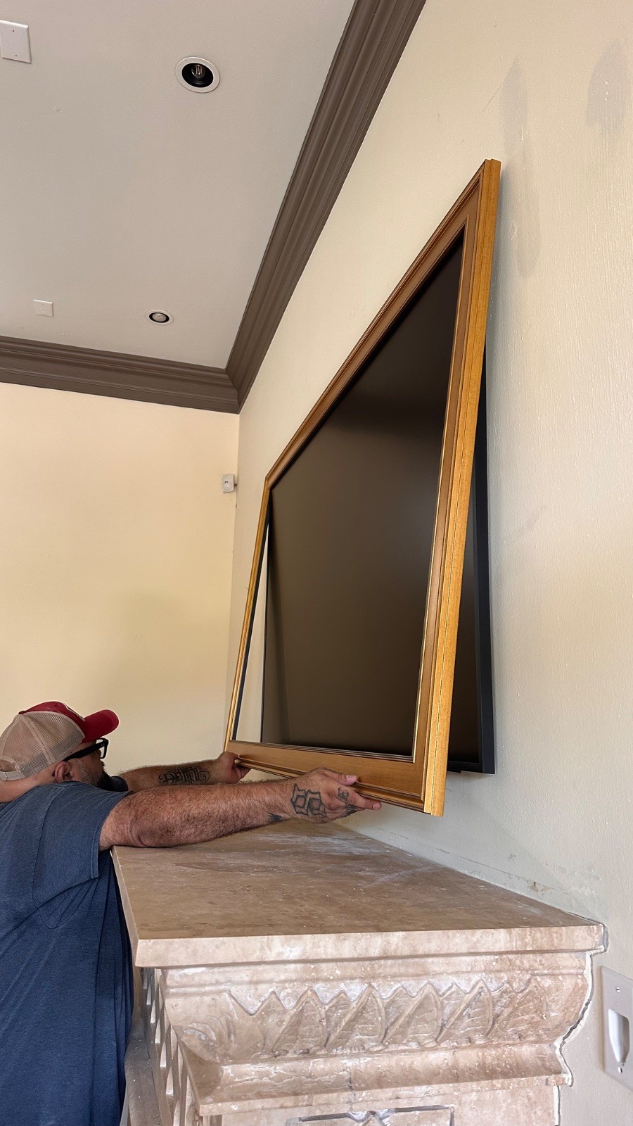 Samsung Frame TV with the custom gold bezel being fitted on the mantle