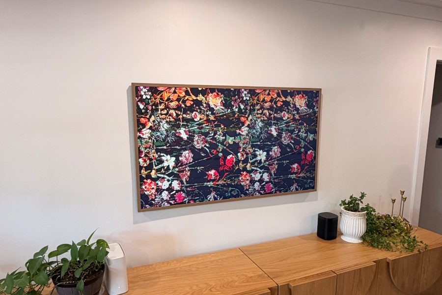 Samsung Frame TV in art mode with a wood bezel, mounted flush above a long oak sideboard, installed by Juan in Houston