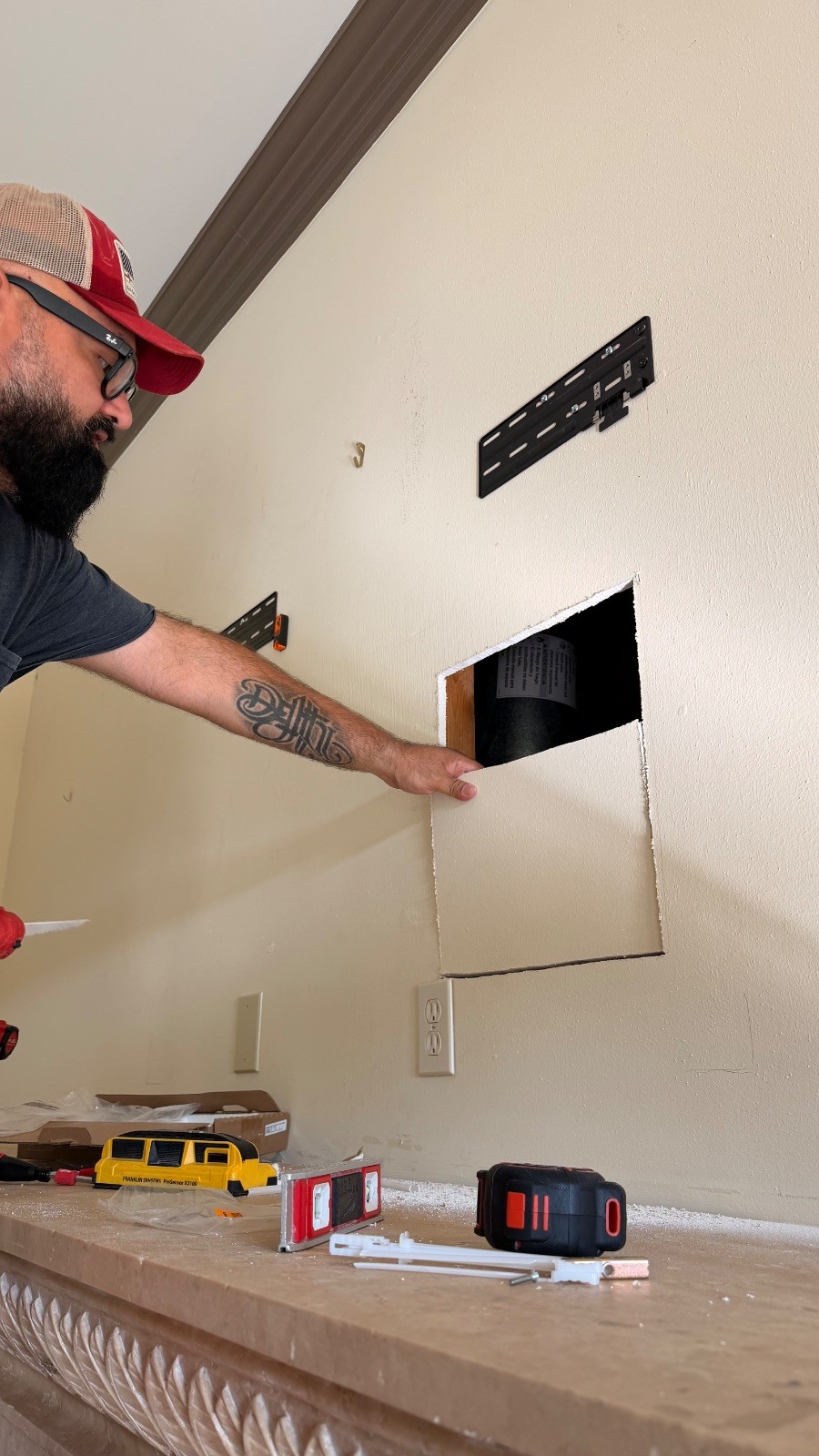 Juan removing the drywall cutout below the TV bracket