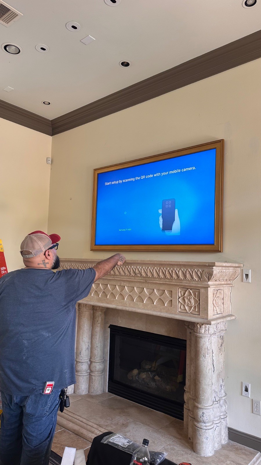 Juan finishing a flush-mounted Samsung Frame TV above a stone fireplace
